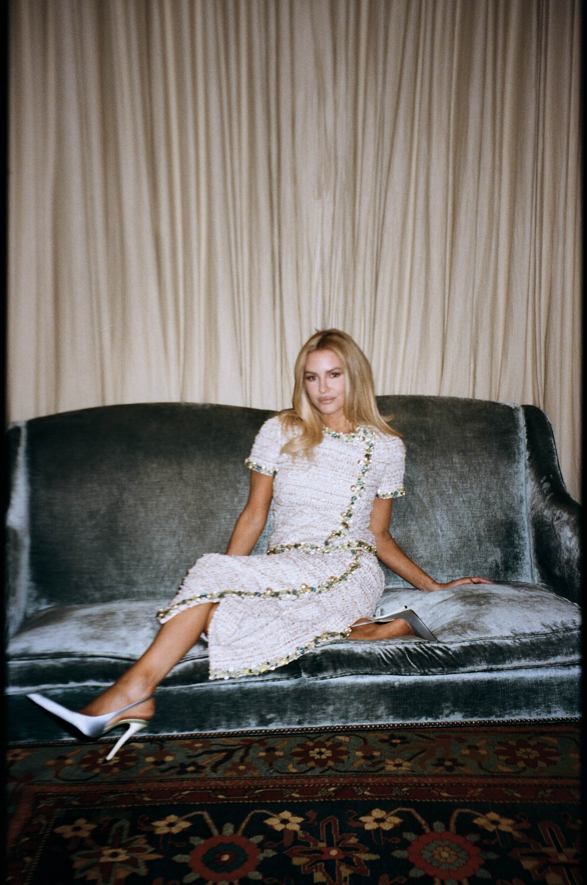 Blonde model on velvet sofa in tweed dress