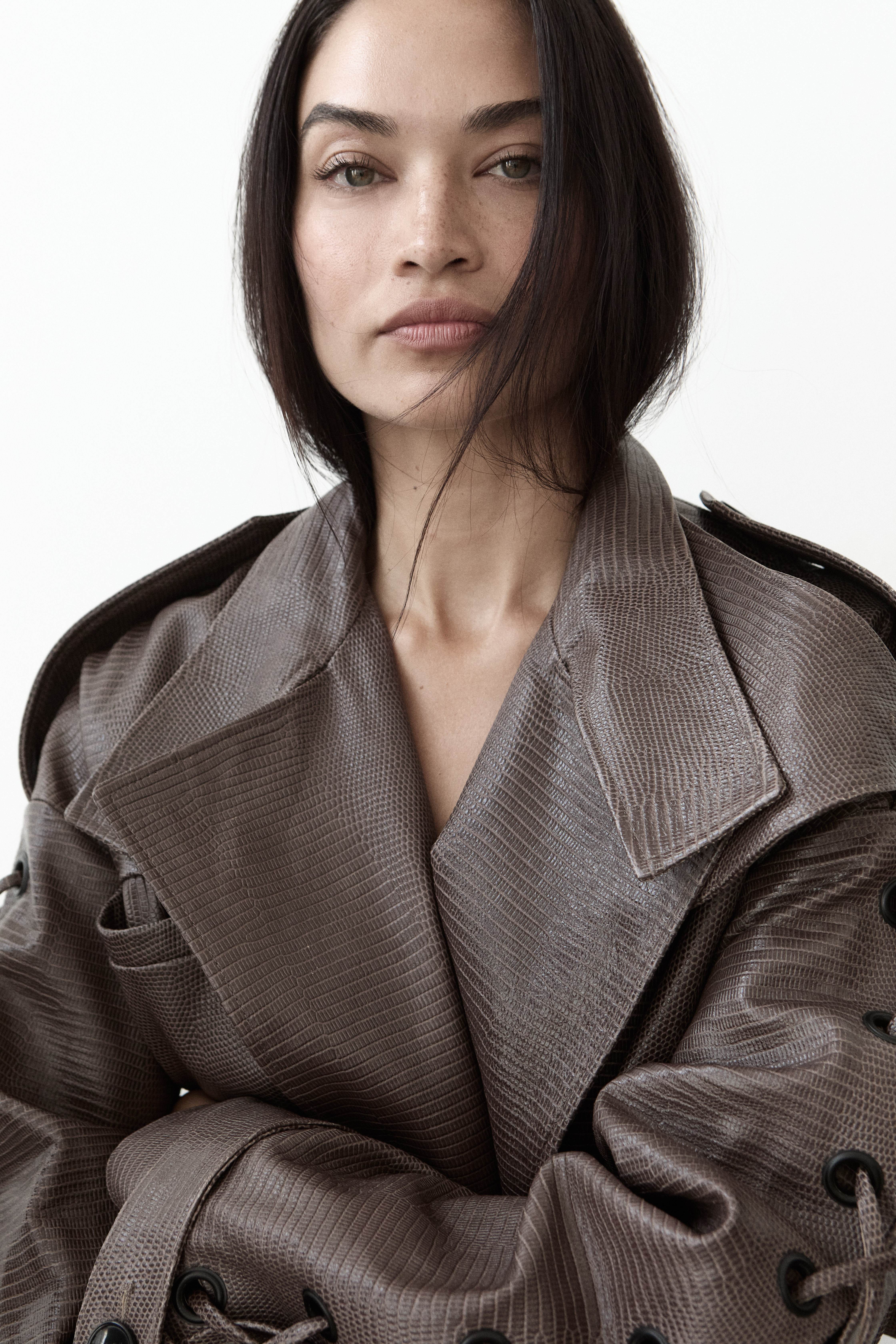 Model in taupe textured leather trench