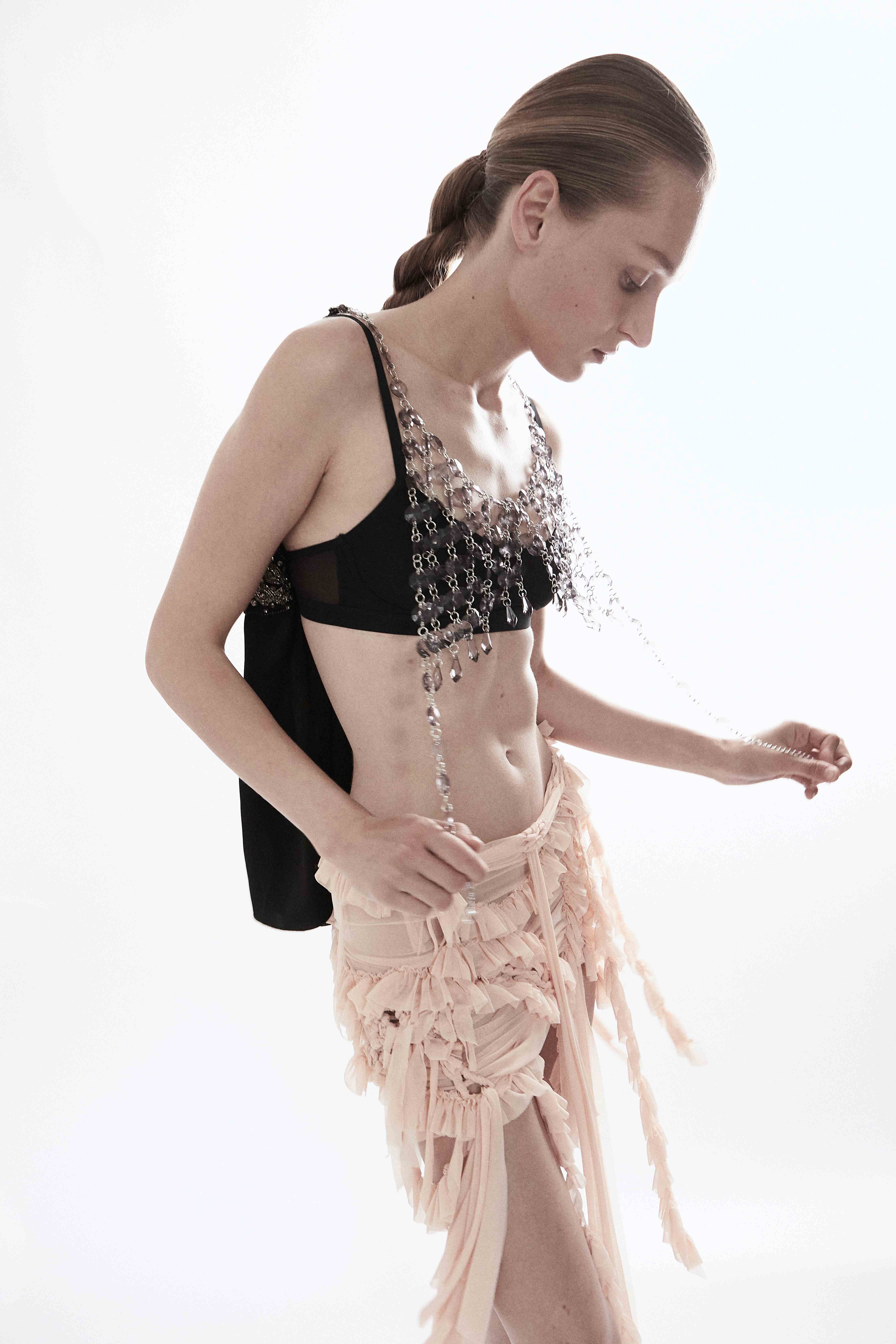 Model in black top with crystal necklace pink ruffled skirt