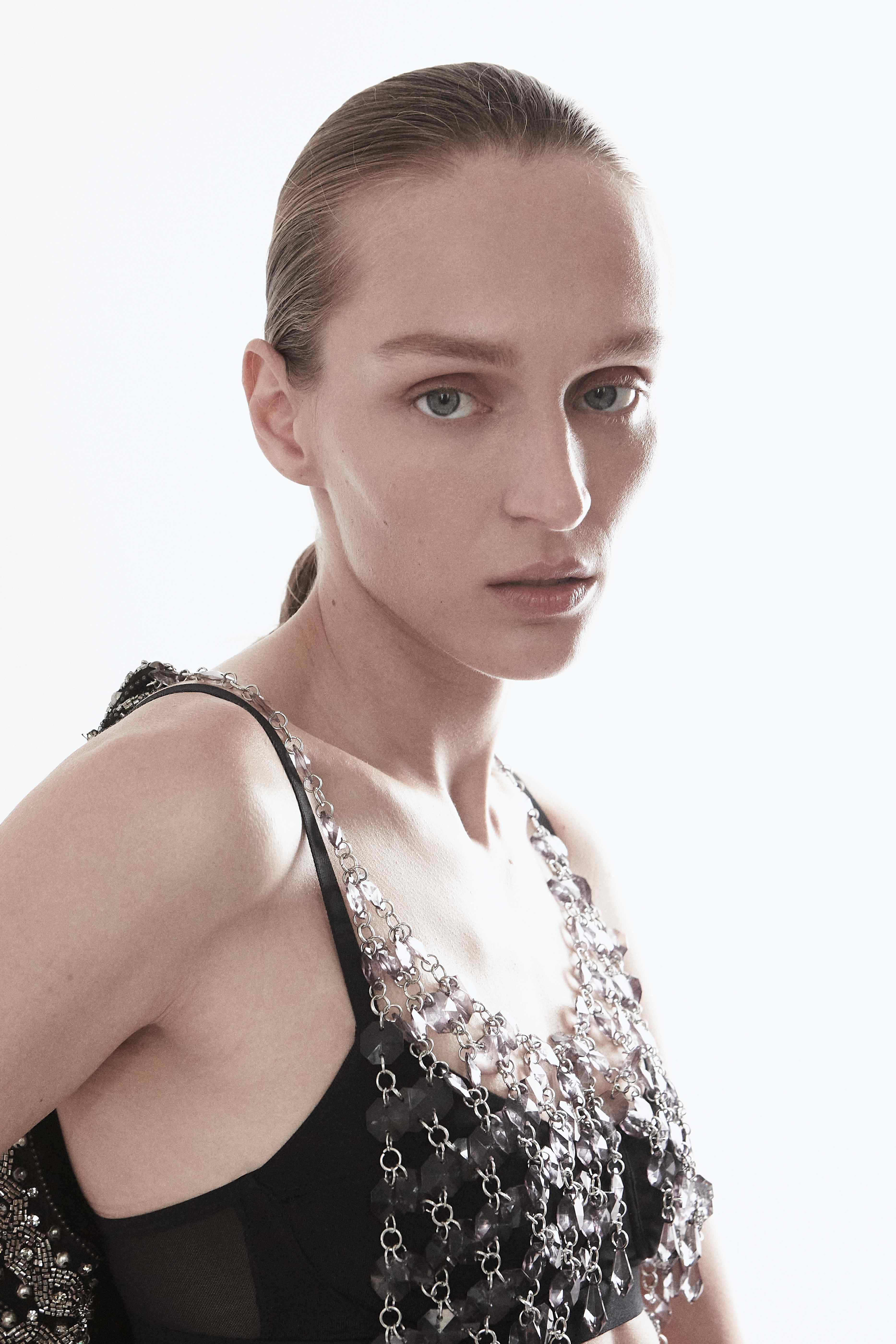 Model with slicked hair crystal necklace black top