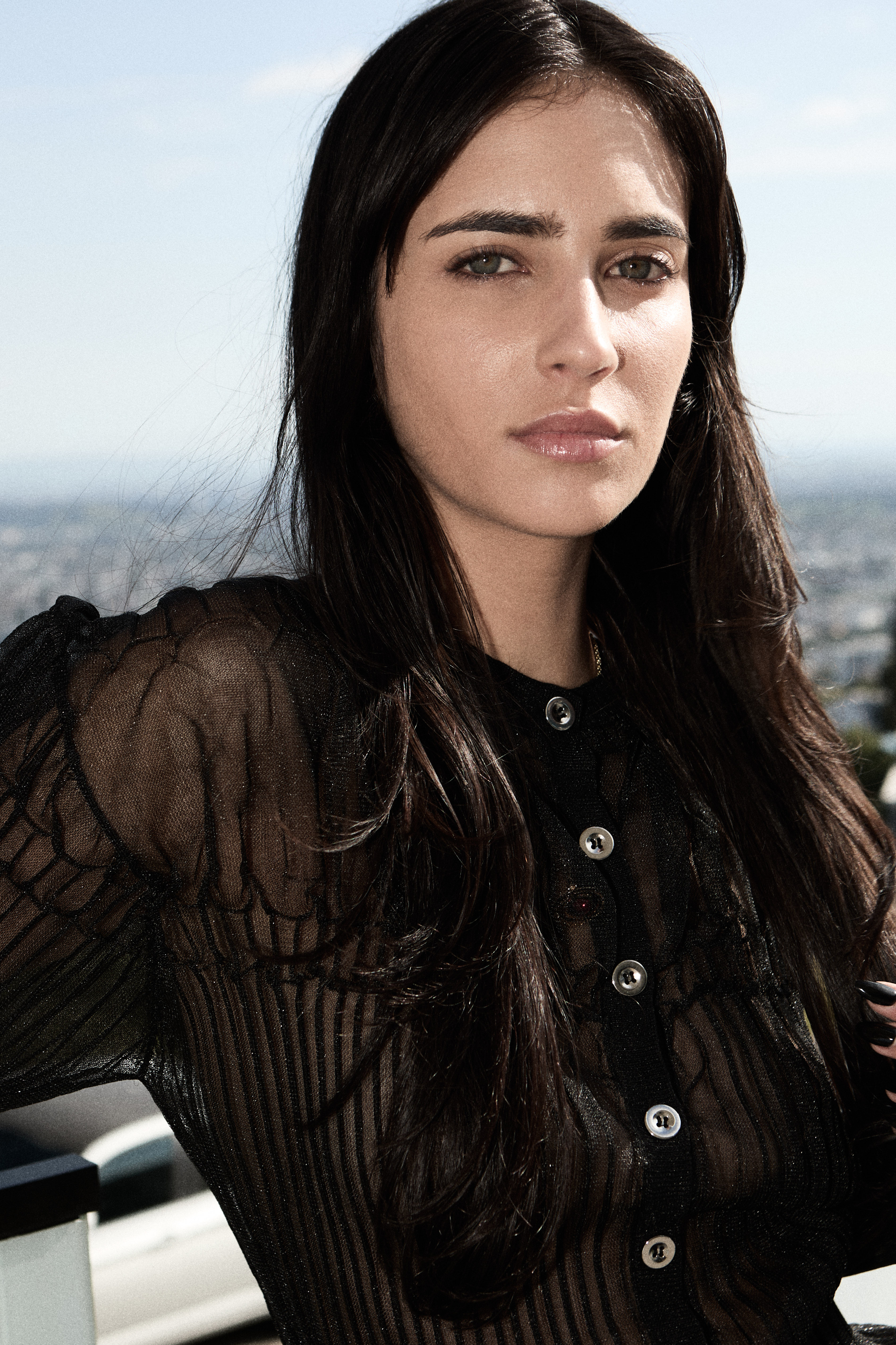 Close-up portrait model in black sheer top city skyline