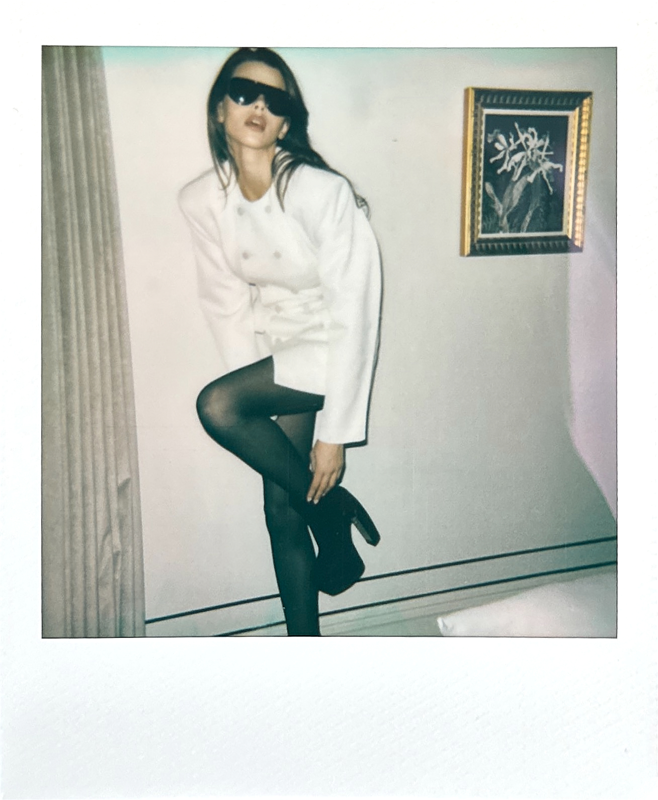 Polaroid model in white blazer black tights sunglasses