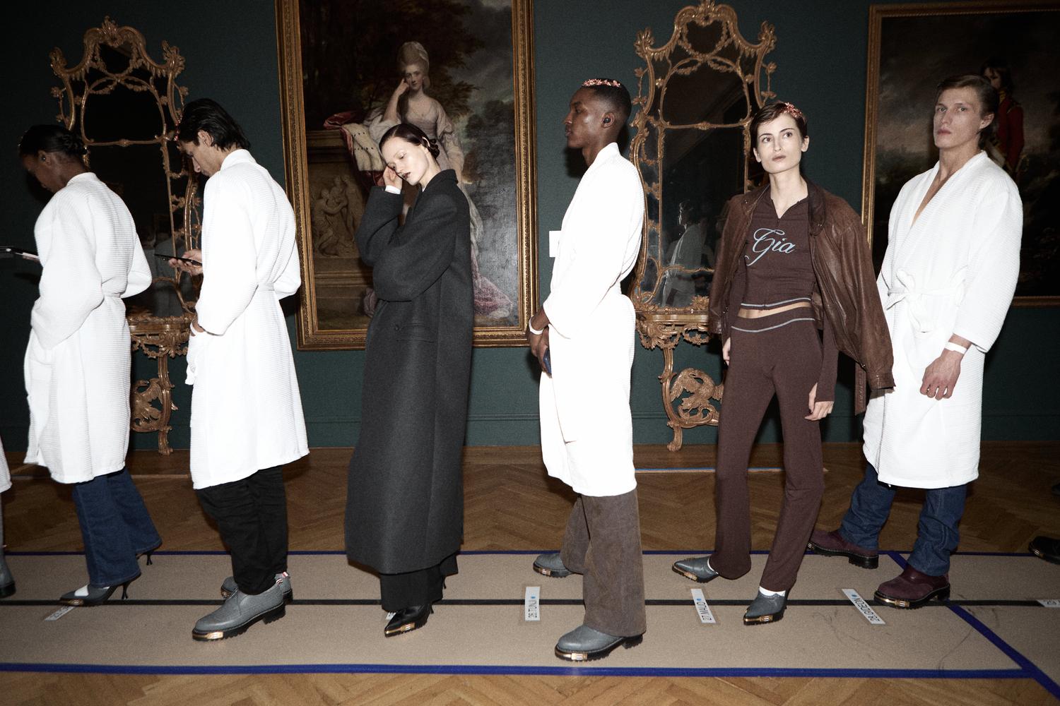 Art gallery scene with models in formal white coats and black wear
