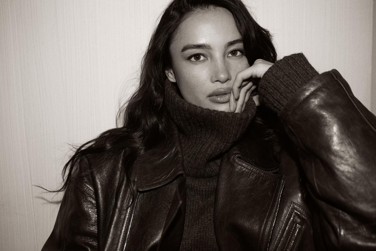 Black and white woman with dark leather jacket and turtleneck